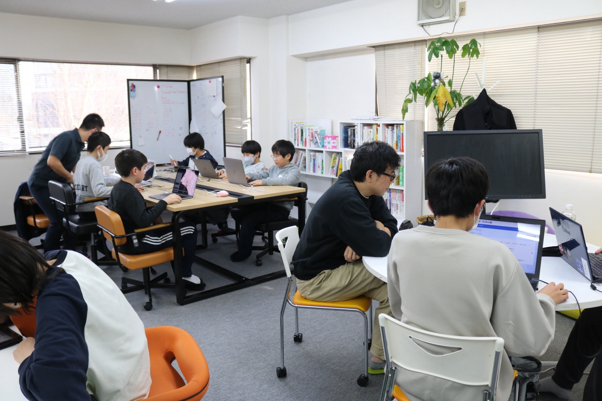 教室でノートパソコンに向かう生徒と、そばで見守る講師